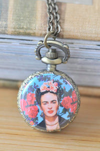 Frida Kahlo pocket watch necklace with portrait surrounded by red roses on a blue background