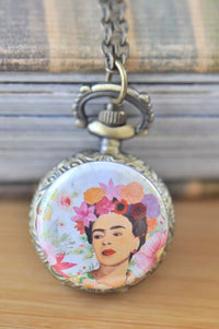 Bronze pocket watch necklace with Frida Kahlo floral portrait pendant against a bookshelf background