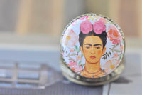 Close-up of Frida Kahlo pocket watch pendant surrounded by watercolour flowers