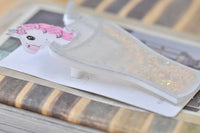 Angled view of unicorn milkshake brooch showing glitter fill and clear acrylic edges
