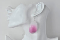 Pink onion drop earring worn on ear for scale