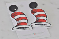 Close-up of red and white striped hat earrings against white card
