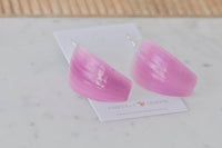 Close-up of glossy resin onion earrings showing pink ombre curve