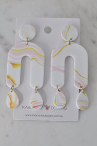 White acrylic drop earrings with pink and yellow marble swirl in arch and teardrop shapes on card