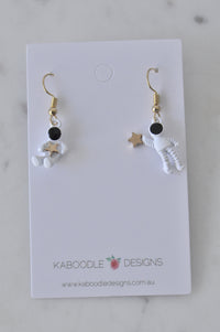 White enamel astronaut charm earrings with gold star detail on Kaboodle Designs card