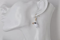 Close-up of astronaut earring worn on ear showing enamel finish and gold star