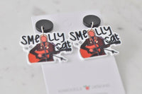 Pair of Smelly Cat acrylic earrings on Kaboodle Designs branded card, angled view