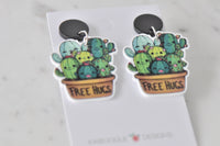 Close-up of Free Hugs cactus earrings showing terracotta pot and cactus faces