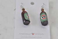Overhead view of two VB beer bottle earrings on card showing bottle base and cap detail