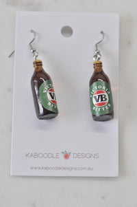 Pair of resin VB beer bottle drop earrings on a Kaboodle Designs card, front view