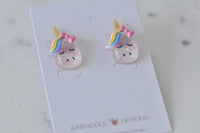 Overhead view of two glitter unicorn earrings on white display card