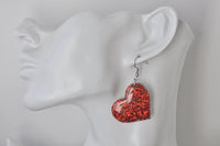 Red glitter heart earring shown on a display ear for scale