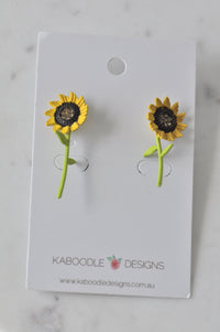 Pair of sunflower stud earrings with long green stems on Kaboodle Designs card