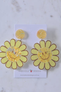 Yellow sunflower drop earrings with glitter star shaker smiley centres on Kaboodle card