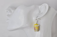 Close-up of popcorn earring worn on ear, showing bucket shape and topping detail