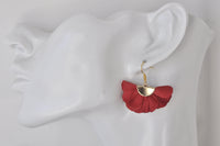 Red fabric fan flower earring shown worn on an ear for scale