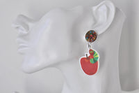 Close-up of caterpillar and apple acrylic earring worn on ear, showing glossy printed detail