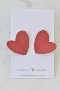 Two matte red heart stud earrings on a Kaboodle Designs card, front view