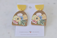 Front view of pair of mustard boho flower earrings on white card