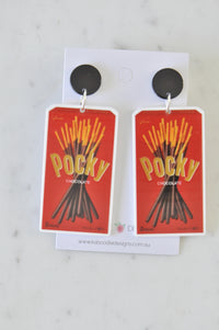 Pair of acrylic Pocky chocolate box drop earrings with black round studs on card