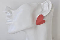 Close-up of a red heart earring worn on a display ear model, side profile