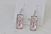 Rectangular dangle earrings printed with a boho dreamcatcher, feathers and pink florals on silver hooks