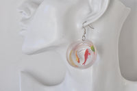 Close-up of goldfish bowl earring worn on ear, showing glossy resin dome