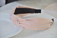 Close-up side profile of pink and blue striped headband showing knot detail and inner band