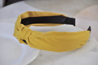Side view of mustard headband showing black underside and knot shape