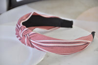 Close-up angled view of pink striped headband showing knot detail and black underside