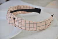 Close-up of pastel pink checkered headband showing fabric knot detail