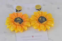 Sunflower earrings viewed close up showing textured dark centre and glossy petals