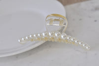 Close-up angled view of pearl claw clip showing hinge mechanism and clasp teeth