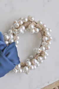 Close-up of faux pearl beads clustered around scrunchie band with blue fabric tie