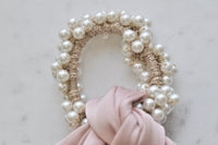 Close-up of faux pearl beading wrapped around scrunchie base with pink bow tails