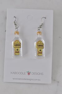 Resin gin bottle drop earrings with gold cap and yellow label, front view on card