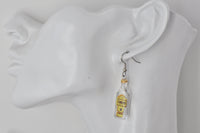 Gin bottle earring shown worn on ear for scale