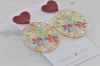 Angled view of both floral gold foil earrings resting on Kaboodle Designs card