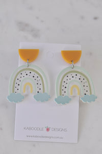 Pair of resin rainbow dangle earrings with mustard stud tops on Kaboodle Designs card