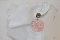 Carousel earring shown on ear, pink disc with white and gold horse print