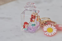 Perspex bottle keychain with miniature mermaid figure, pressed flowers and pink glitter liquid