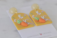Close-up of mustard resin earring showing 3D carrot charm and bunny print detail