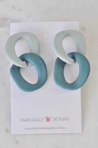 Pair of sage and teal matte acrylic link earrings on a Kaboodle Designs card