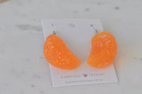 Close-up of mandarin earrings against marble surface showing textured resin finish