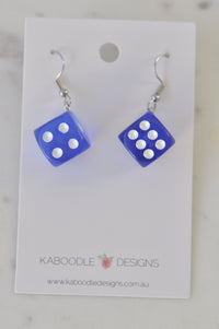 Pair of translucent blue dice earrings with white pips on Kaboodle Designs card