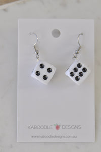 White acrylic dice earrings on card showing black pips, one die reading four and one showing six