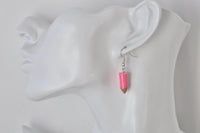 Pink pencil earring shown on ear for scale