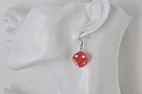Single red dice earring shown worn on ear, hanging from a silver-tone hook