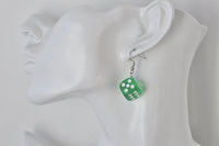 Single green dice earring shown worn on ear for scale