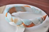 Top-down view of braided fabric headband showing tie-dye pattern and plait detail